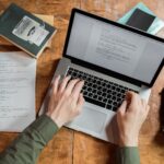 person using macbook pro on brown wooden table