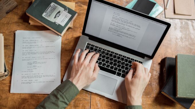 person using macbook pro on brown wooden table